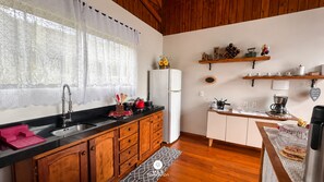 Chalé Caminho do Sol 1 - Jacuzzi e Bônus Culinário | Private kitchen | Fridge, cookware/dishes/utensils, dining table, kitchen island - Chalé Caminho do Sol (Rancho Queimado)