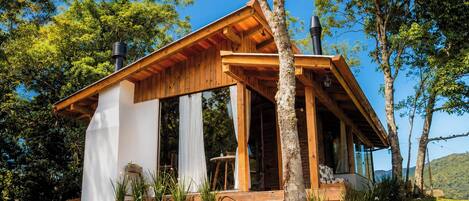Una cabaña de madera con techo inclinado, ventanas amplias y un porche.