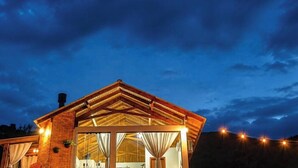 A modern building with a glass facade and a brick exterior, featuring a large open space with curtains and a visible interior. - Chalé Caminho do Sol (Rancho Queimado)