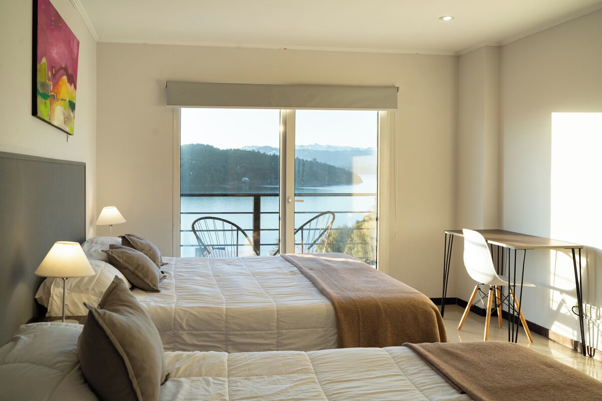 A bedroom with a bed, bedside lamps, a desk, and a chair.