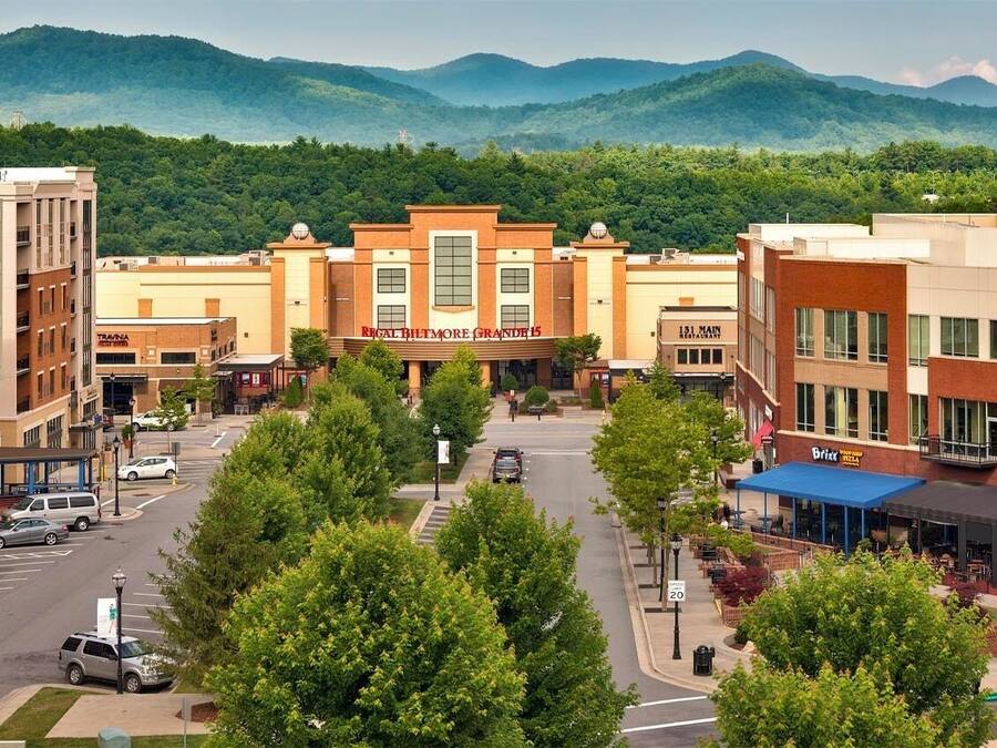 A downtown area with a mix of commercial and residential buildings, a central plaza, and a mountain backdrop.