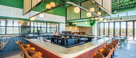 Un espace bar moderne avec un comptoir incurvé, de nombreux tabourets et un mur décoratif en briques.