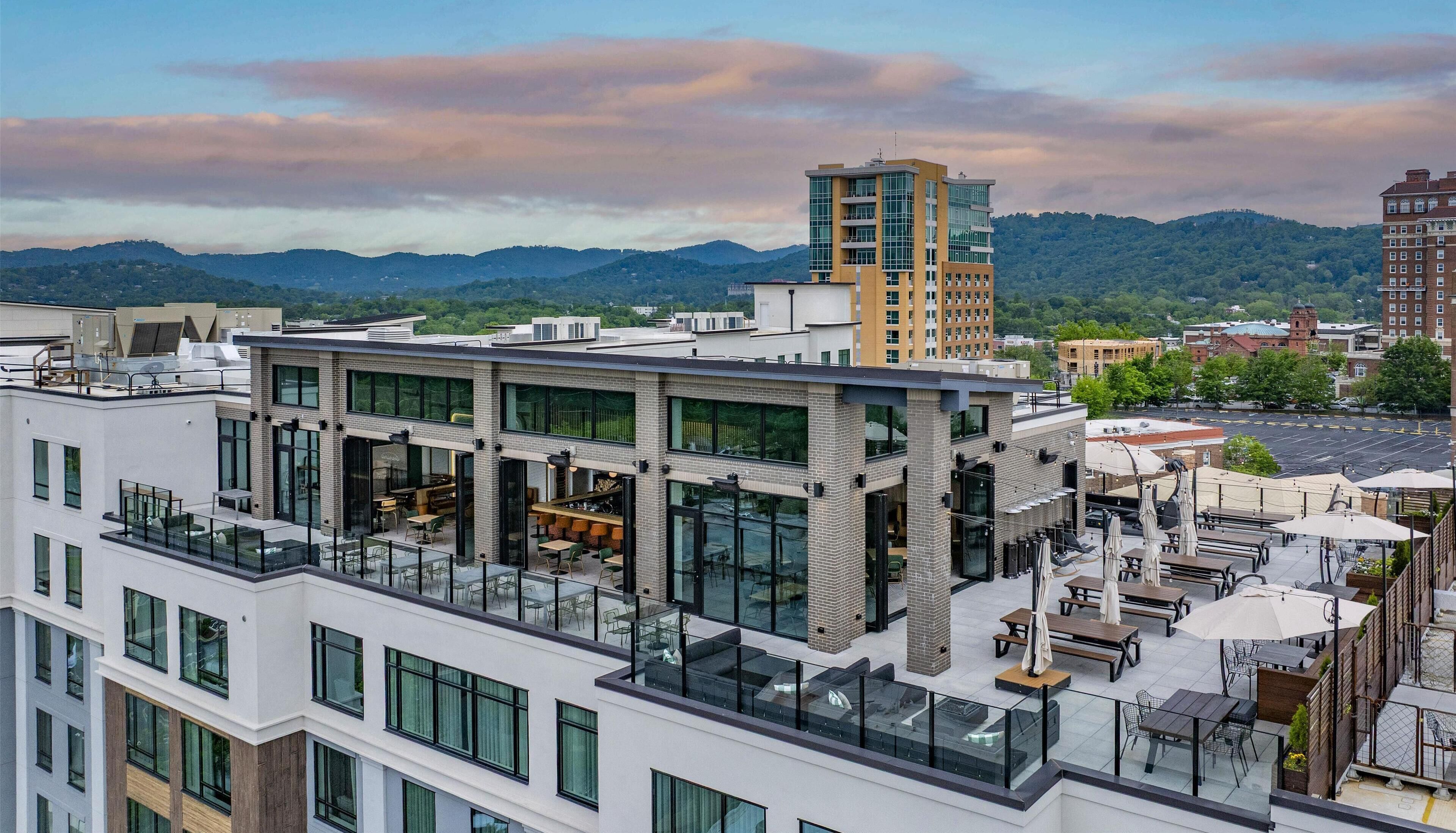 A modern building with multiple floors, large windows, and outdoor seating areas.