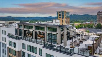 A modern building with multiple floors, large windows, and outdoor seating areas.