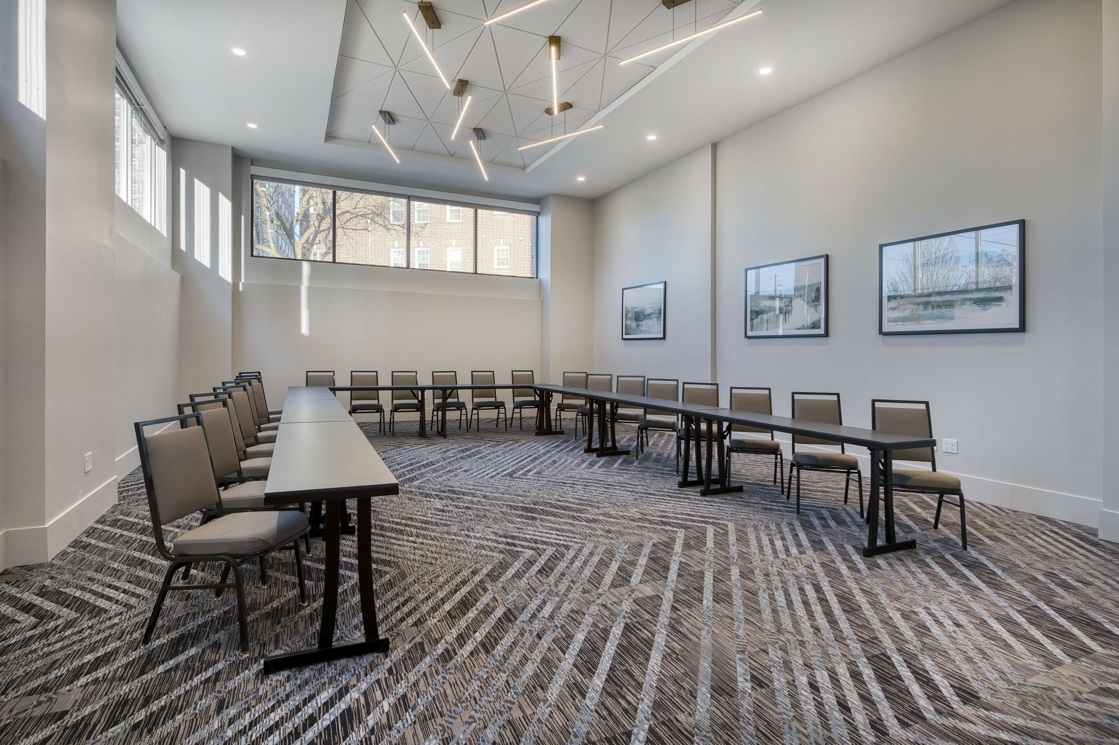 Une salle de conférence avec une longue table et des chaises, de grandes fenêtres et des œuvres d’art encadrées accrochées aux murs.