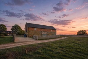 Une ferme en briques avec une allée en gravier et une clôture en bois.