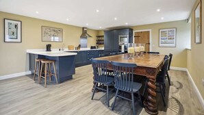 Una cocina moderna con una isla central, taburetes de bar y una mesa de comedor con sillas.