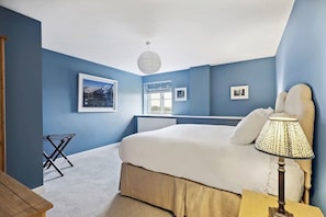 A bedroom with a bed, a hanging light fixture, and a window.