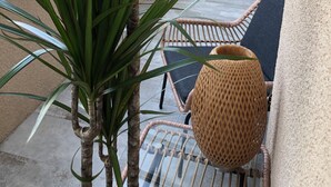 A balcony with a potted plant, wicker chairs, and a wicker basket. - Maison de Midi (Ginestas)