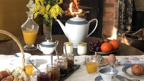 A breakfast table with a variety of food items, a teapot, and a fireplace in the background. - Maison de Midi (Ginestas)