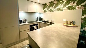 A modern kitchen with white cabinets, a countertop, and a backsplash with a tropical leaf pattern.