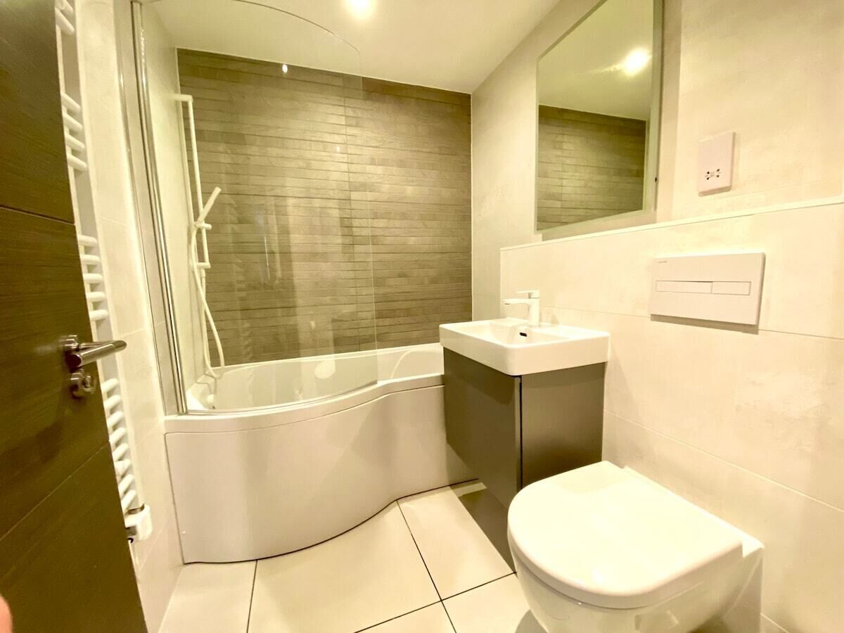A modern bathroom with a bathtub, toilet, and sink.