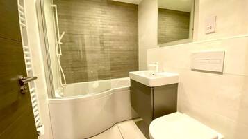 A modern bathroom with a bathtub, toilet, and sink.