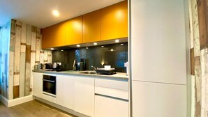 A modern kitchen with white cabinets, a stainless steel sink, and a built-in oven.