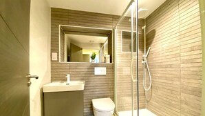 A modern bathroom with a glass-enclosed shower, a white sink, and a toilet.