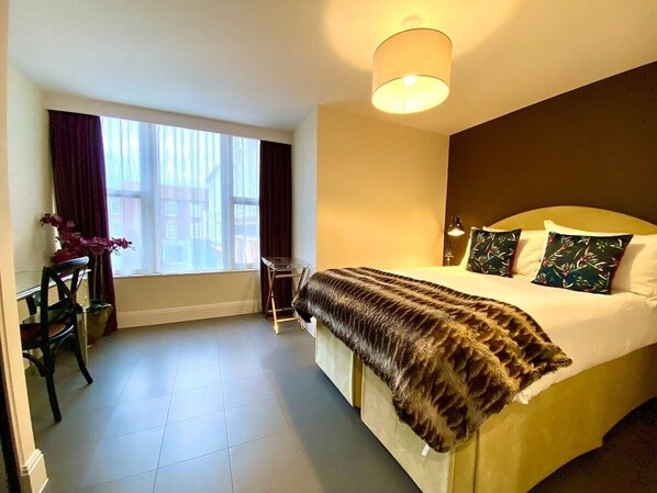 A hotel room with a bed, a desk, and a chair.