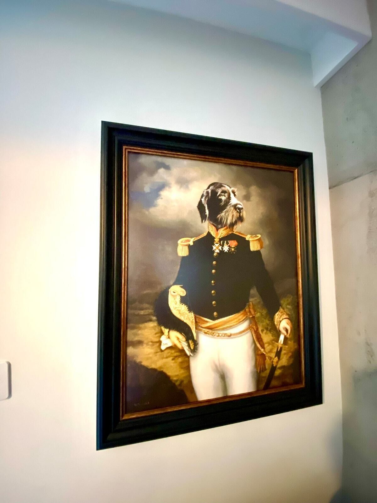 A framed portrait of a person in military uniform with medals, hanging on a wall.