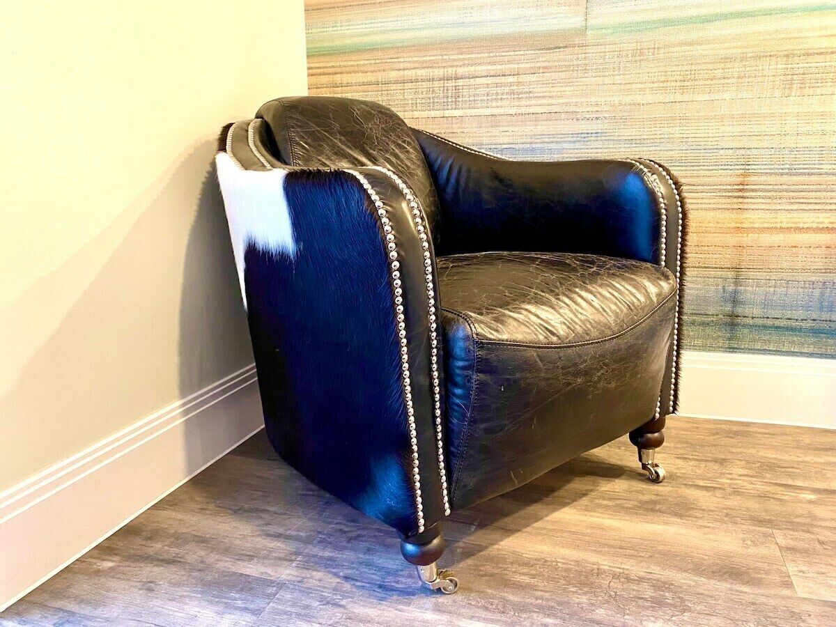 Un sillón de esquina con tela azul oscuro y blanco, decorado con un borde perlado, ubicado frente a una pared con textura.