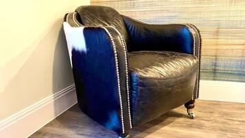 Un sillón de esquina con tela azul oscuro y blanco, decorado con un borde perlado, ubicado frente a una pared con textura.