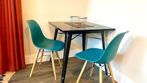A small dining area with a table and two teal chairs.
