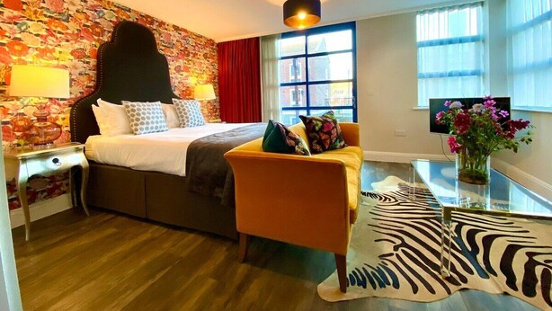 A hotel room with a bed, a sofa, a TV, and a window with curtains.