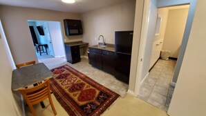 A compact kitchen with dark cabinetry, a built-in sink, and a black refrigerator. - Studio - kitchenette (Coeur d'Alene)