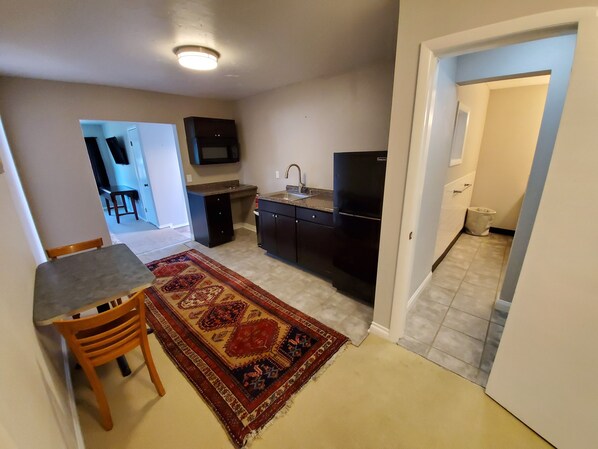 A compact kitchen with dark cabinetry, a built-in sink, and a black refrigerator. - Studio - kitchenette (Coeur d'Alene)