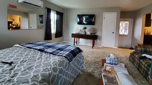 A bedroom with a bed, a TV, a desk, and a sofa. - Studio - kitchenette (Coeur d'Alene)