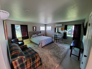 A bedroom with a bed, a desk, a chair, a sofa, and a TV. - Studio - kitchenette (Coeur d'Alene)