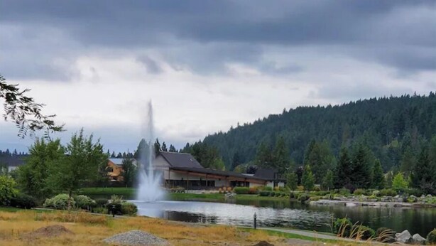 A lodge with a pond and a fountain, surrounded by forested hills. - Studio - kitchenette (Coeur d'Alene)