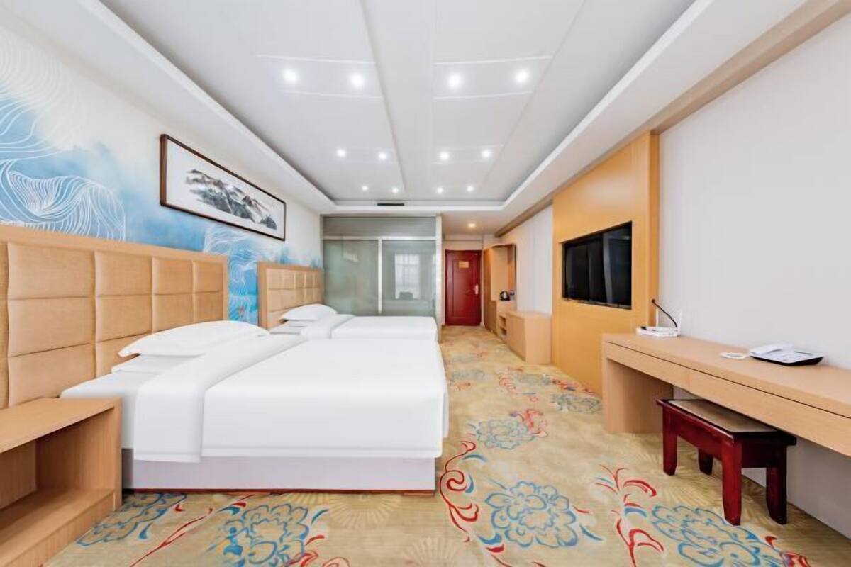 Une chambre d’hôtel équipée d’un lit, de tables de chevet, d’un bureau et d’une télévision.