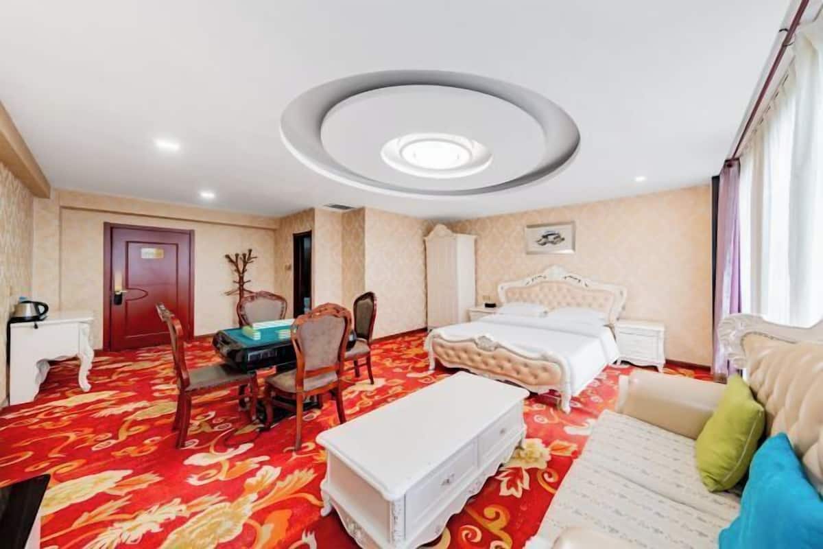 Une chambre d’hôtel avec un grand lit, un bureau et une chaise. Il y a une porte et une fenêtre.