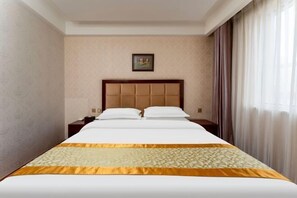 A hotel room with a large bed, a headboard, a nightstand, a framed picture on the wall, and a window with curtains.