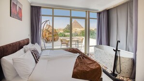A hotel room with a bed, a view of the pyramid, and a balcony with a table and chairs. - Shadow Pyramids View INN (Giza)