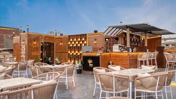 An outdoor seating area with wicker chairs and tables, a bar with a wooden counter, and a sign that reads "Tree Lounge".