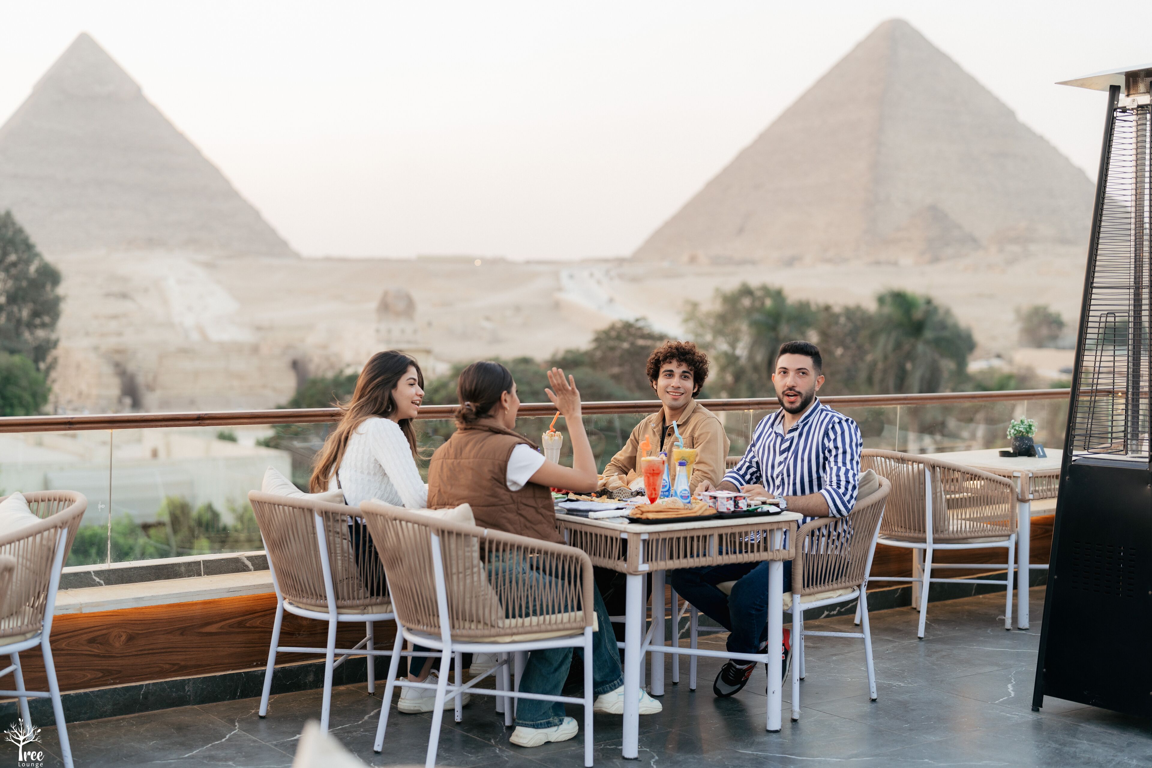 A group of people dining at a table with a view of the pyramids.