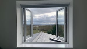 Ein Zimmer mit großem Fenster und Blick auf die Landschaft.
