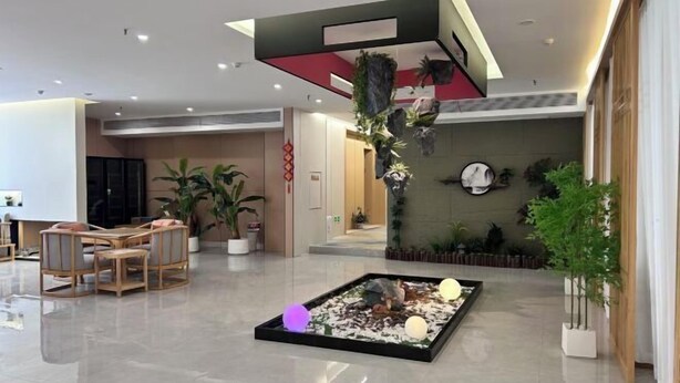 A modern lobby with a central seating area, a decorative water feature, and potted plants. - Jianmen Star Hotel (Jiange)