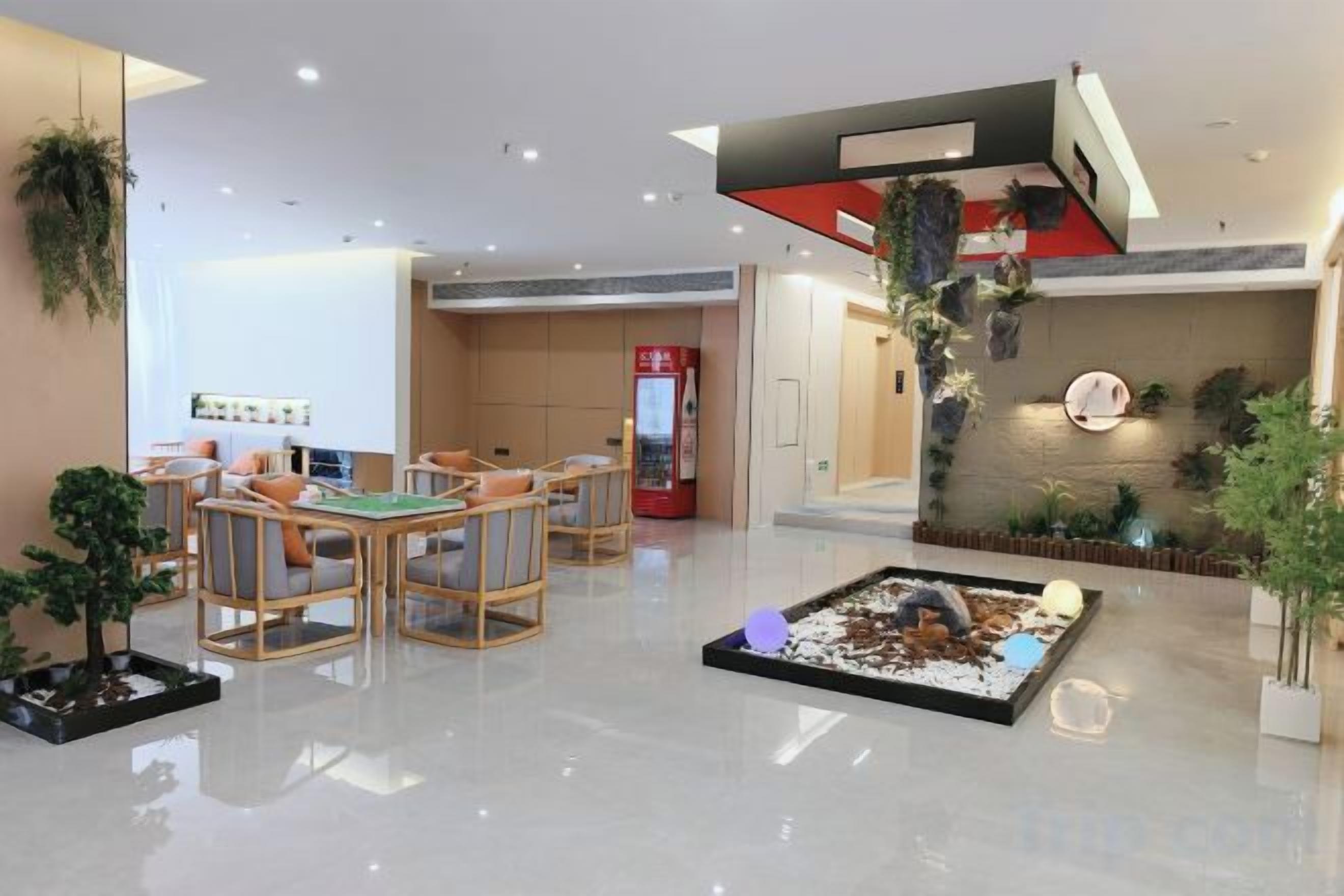 A hotel lobby with a reception desk, seating area, and a small indoor garden.