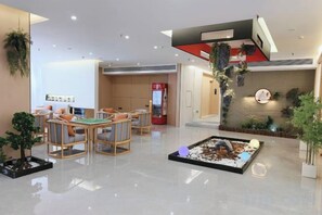 A hotel lobby with a reception desk, seating area, and a small indoor garden. - Jianmen Star Hotel (Jiange)