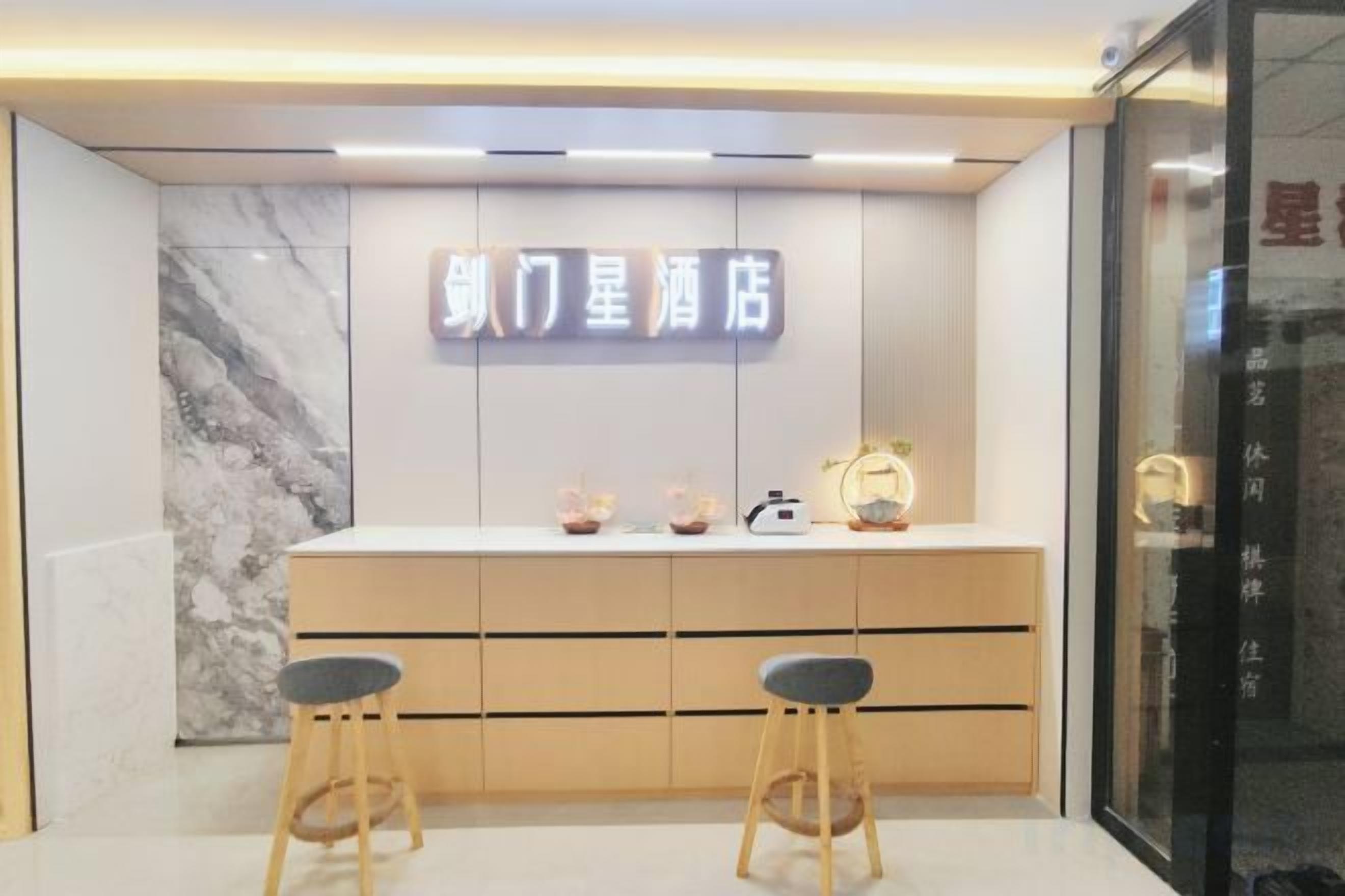 A hotel reception area with a marble wall, a reception desk, two bar stools, and a sign with Chinese characters.