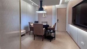 A modern dining area with a table and chairs, a pendant light, and a large TV screen. - Jianmen Star Hotel (Jiange)