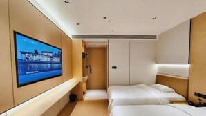 A hotel room with a TV on the wall, two beds, a small seating area, and a door leading to another room. - Jianmen Star Hotel (Jiange)