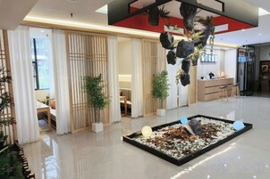 Un moderno vestíbulo de hotel con mostrador de recepción, zona de estar y plantas decorativas.