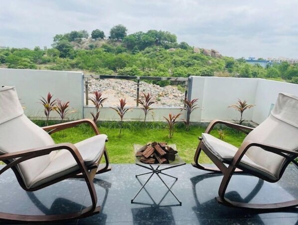 Relax on the rooftop terrace with a serene view of the lush landscape and distant hill.