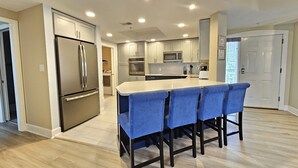 A modern kitchen with a central island, built-in appliances, and a dining area with bar stools. - Amazing Villa w/ Beautiful Views from Balcony! (Hilton Head Island)