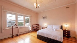 Une chambre à coucher avec un grand lit, des lampes de chevet, un radiateur et une fenêtre donnant sur un beau paysage.