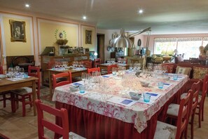 Un comedor con varias mesas dispuestas para una comida, sillas y un amplio ventanal con vistas.