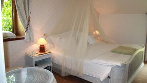 A bedroom with a canopy bed, a bedside table with a lamp, and a small round table. - Casa de Juste (Lousada)