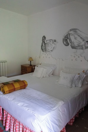 Una cama bien tendida con sábanas blancas, un plaid escocés y un mural en la pared con lechuzas.